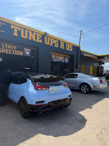 Cars in the open bays under the black and yellow Tune Ups R Us canopy in daylight