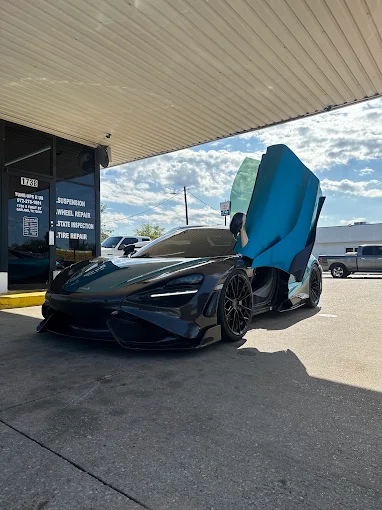 Carbon McLaren parked under the shop canopy with its door raised