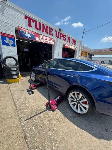 Blue Tesla Model 3 on jack stands in front of the shop for tire service