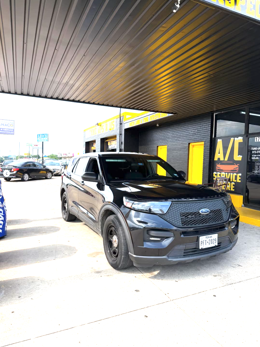 Black Ford Interceptor parked under the yellow-trimmed canopy at the Tune Ups R Us shop entrance