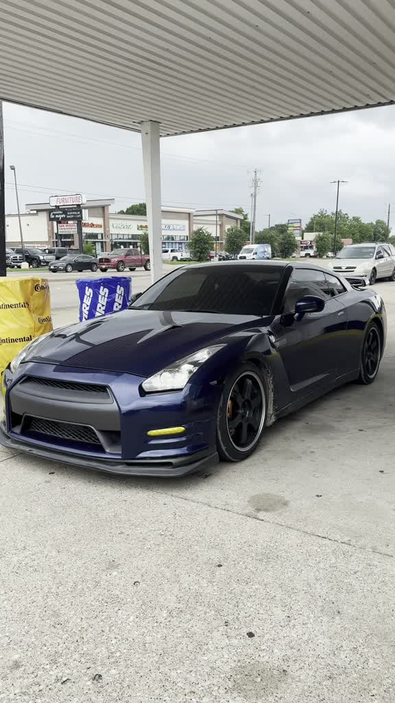 Blue Nissan GT-R under the shop canopy next to fresh tires